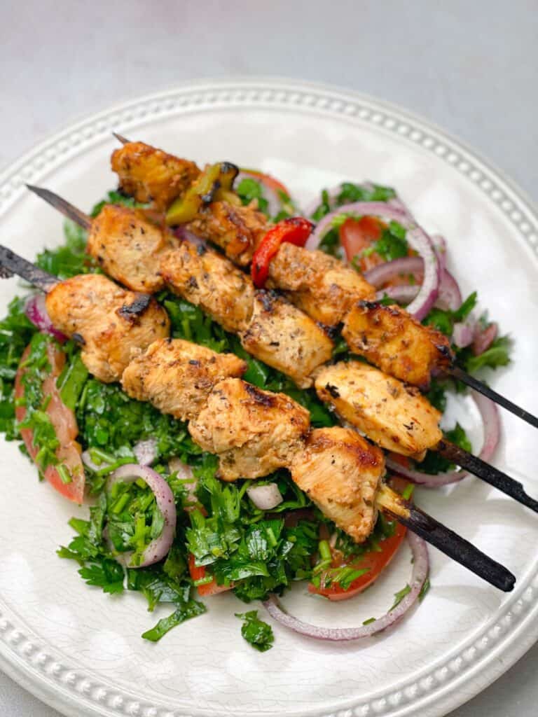 grilled shish taouk skewers with green and red bell peppers served with middle eastern chopped salad