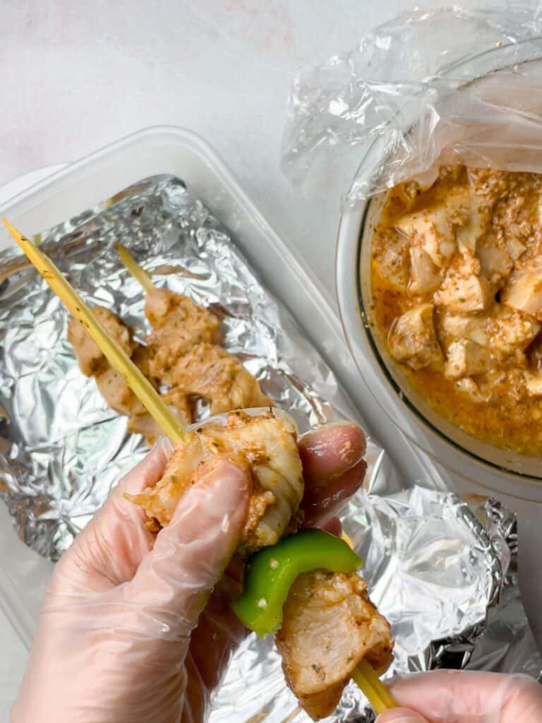 Marinated chicken pieces laced onto skewers with green bell peppers.