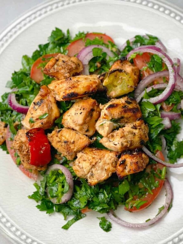 A plate of chicken shish tawook served with sumac red onions salad.