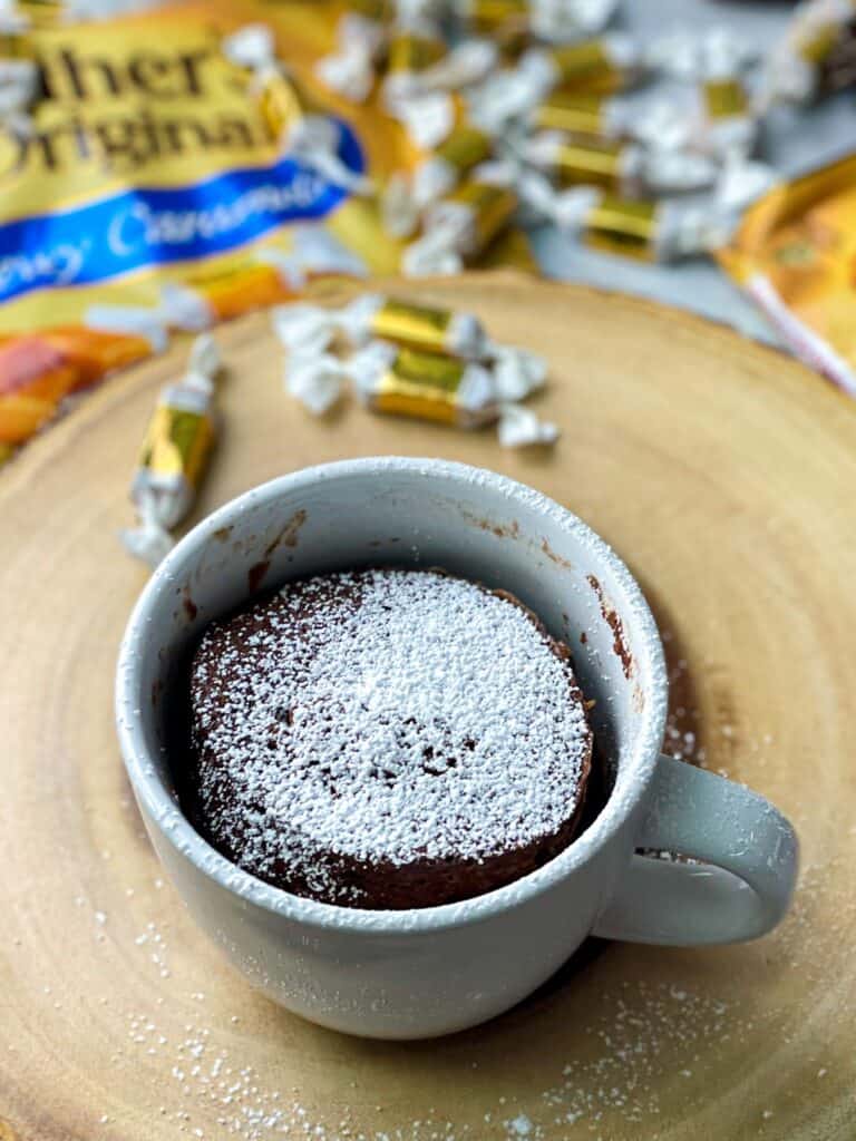 A chocolate caramel mug cake topped with sugar powder is ready to be served