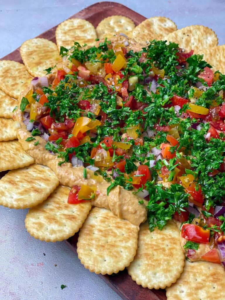 A layer of hummus topped with onion, tomatoes, and chopped parsley with a drizzle of olive oil, salt, and pepper is perfect with your perfect crackers