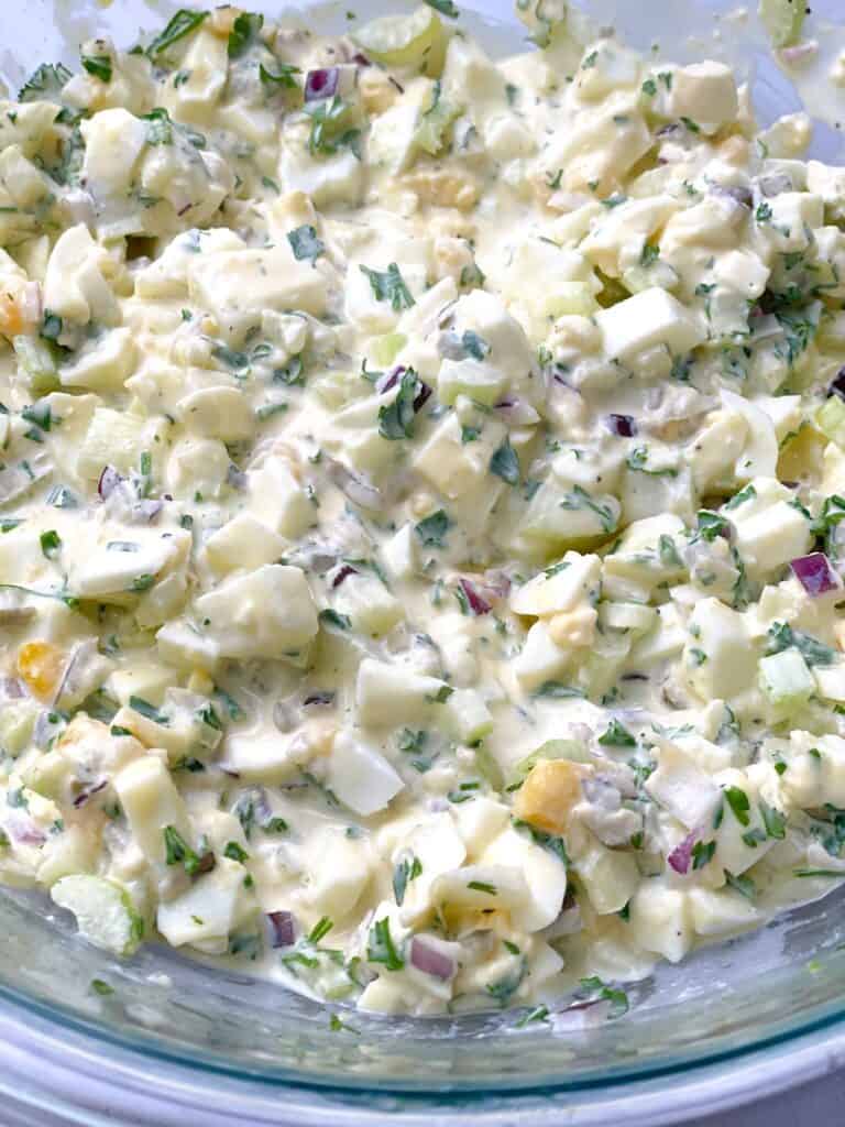 A bowl of healthy and delicious egg salad with mustard dressing and fresh herbs
