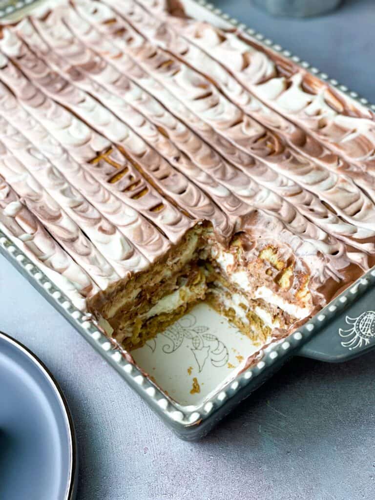 A pan filled with layered graham cracker coffee cake with a missing piece.