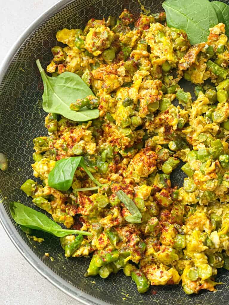 asparagus and eggs skillet garnished with paprika and served with fresh basil leaves