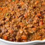 a close-up shot of thick hearty chili served in a white porcelain dish