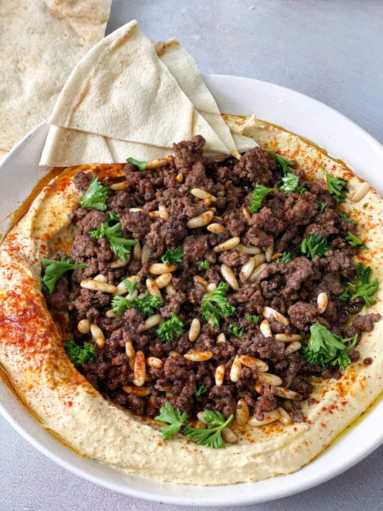 creamy hummus topped with spiced ground beef, pine nuts, fresh parsley and paprika served with a side of sliced pita bread