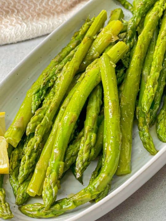 delicious boiled asparagus served with lemon and seasoned with salt and pepper