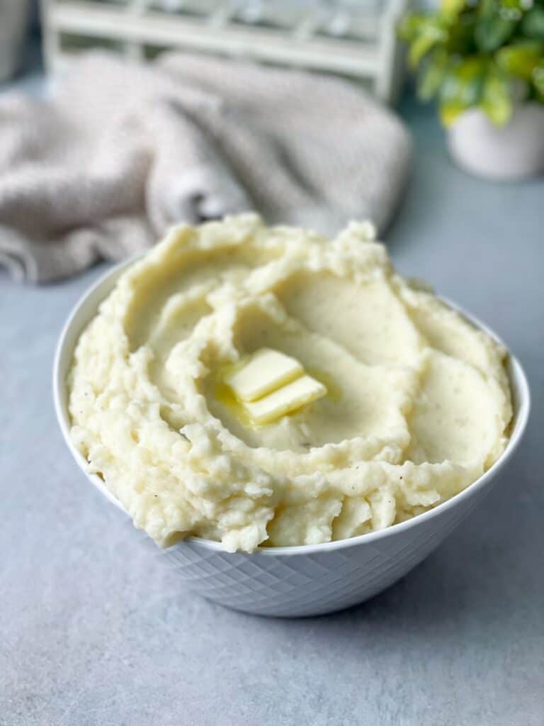 a bowl of creamy mashed potatoes with pieces of butter