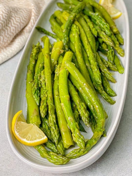 Healthy gluten free Asparagus seasoned with black pepper and salt and served with lemon. 