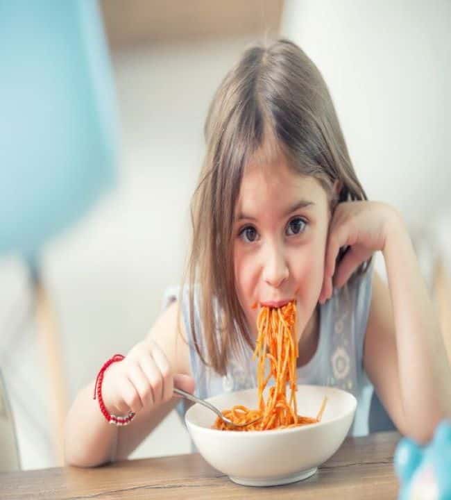 a little girl eating delicious pasta made with kid-friendly sauce
