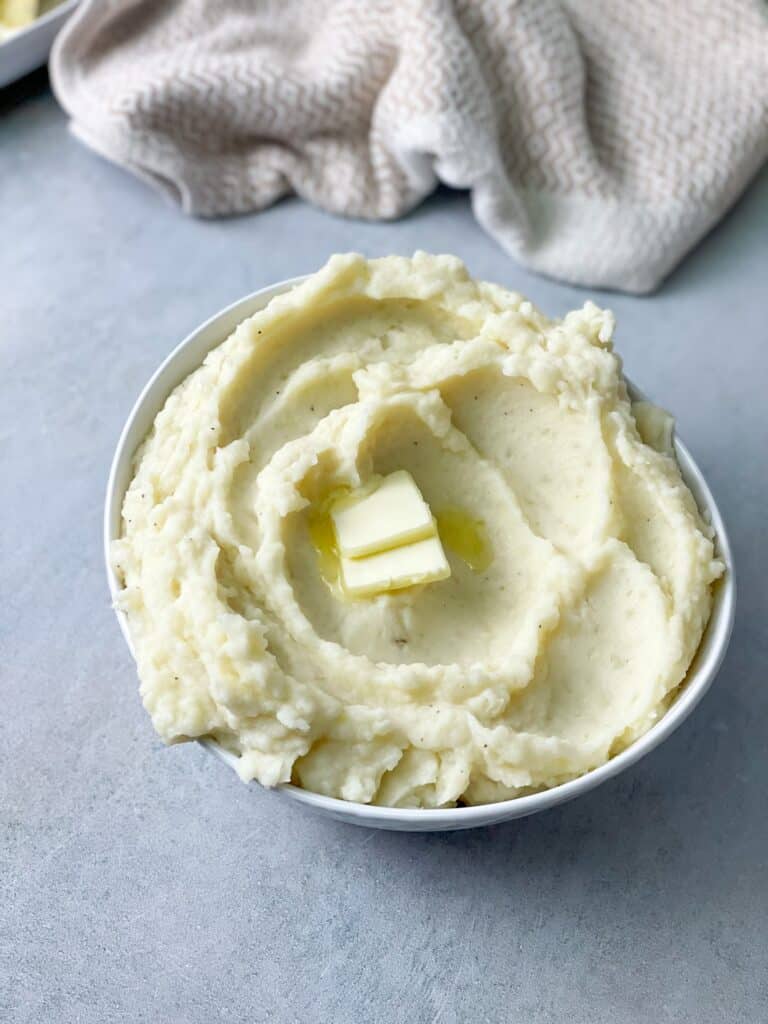 a top view of creamy mashed potatoes bowl with pieces of butter