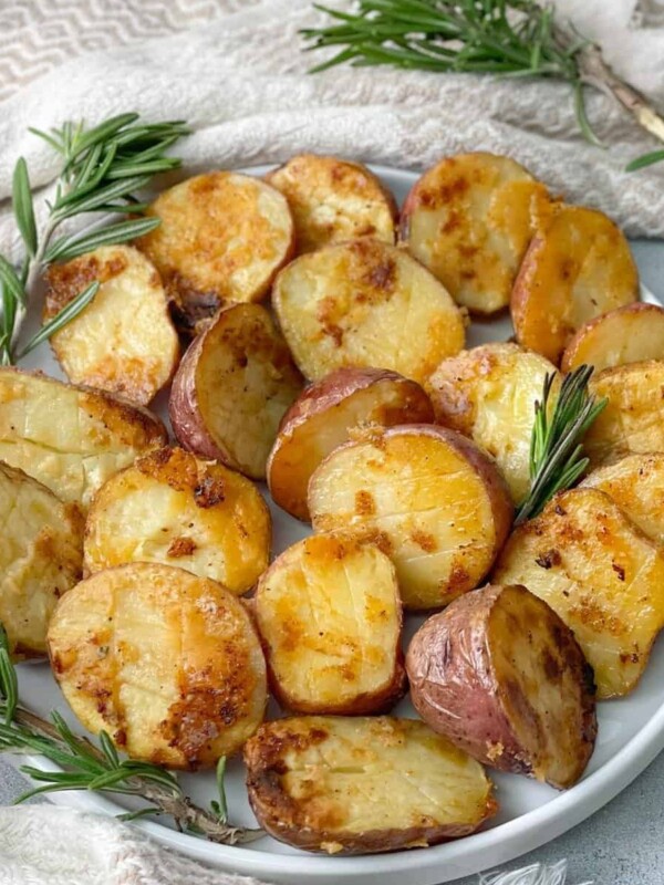 a plate of crispy baked potatoes with parmesan and seasoned with olive oil, parmesan, garlic, and rosemary