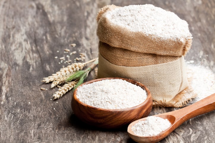 White flour in a sac, a bowl, and a spoon