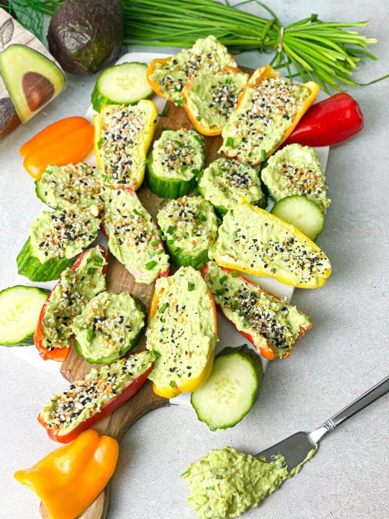 colorful peppers and cucumber slices are topped with the avocado and cream cheese spread and sprinkled with everything but bagel seasoning