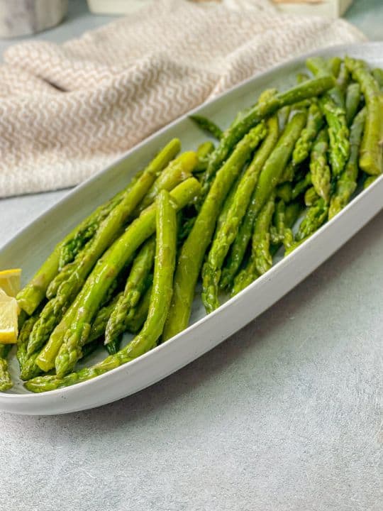 an incredibly tasting boiled asparagus seasoned with pepper and salt and served with lemon