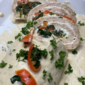 chicken roulade with vegetables served with white sauce on top