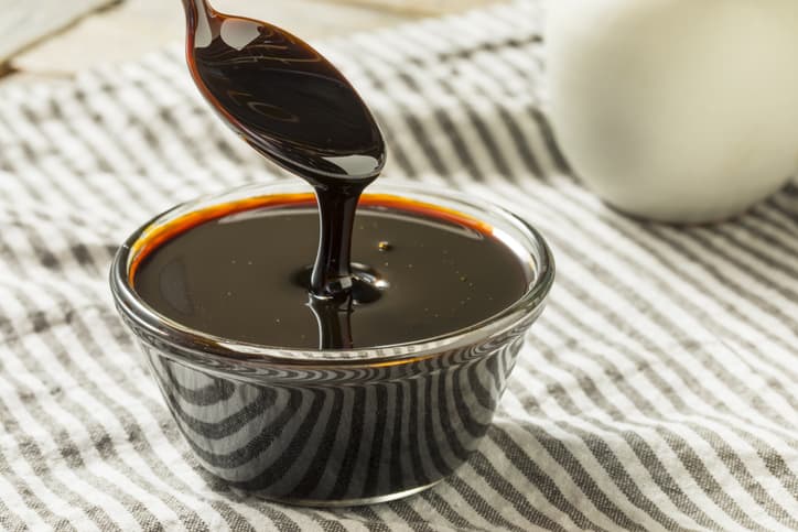 Homemade organic black cane sugar molasses in a glass small bowl on a cotton towel