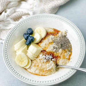 a bowl of steel cut oats with banana, coconut shreds, and berries toppings