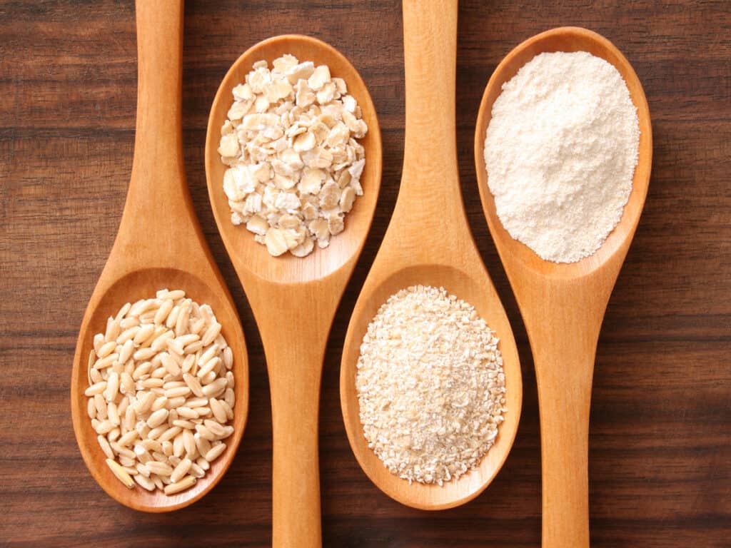 Four spoons with oat derivatives (grains,rolled oats,bran,flour)