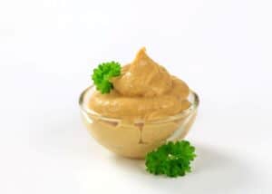 spicy chipotle aioli in a small glass bowl decorated with leaves of green parsley