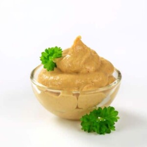 spicy chipotle aioli in a small glass bowl decorated with leaves of green parsley
