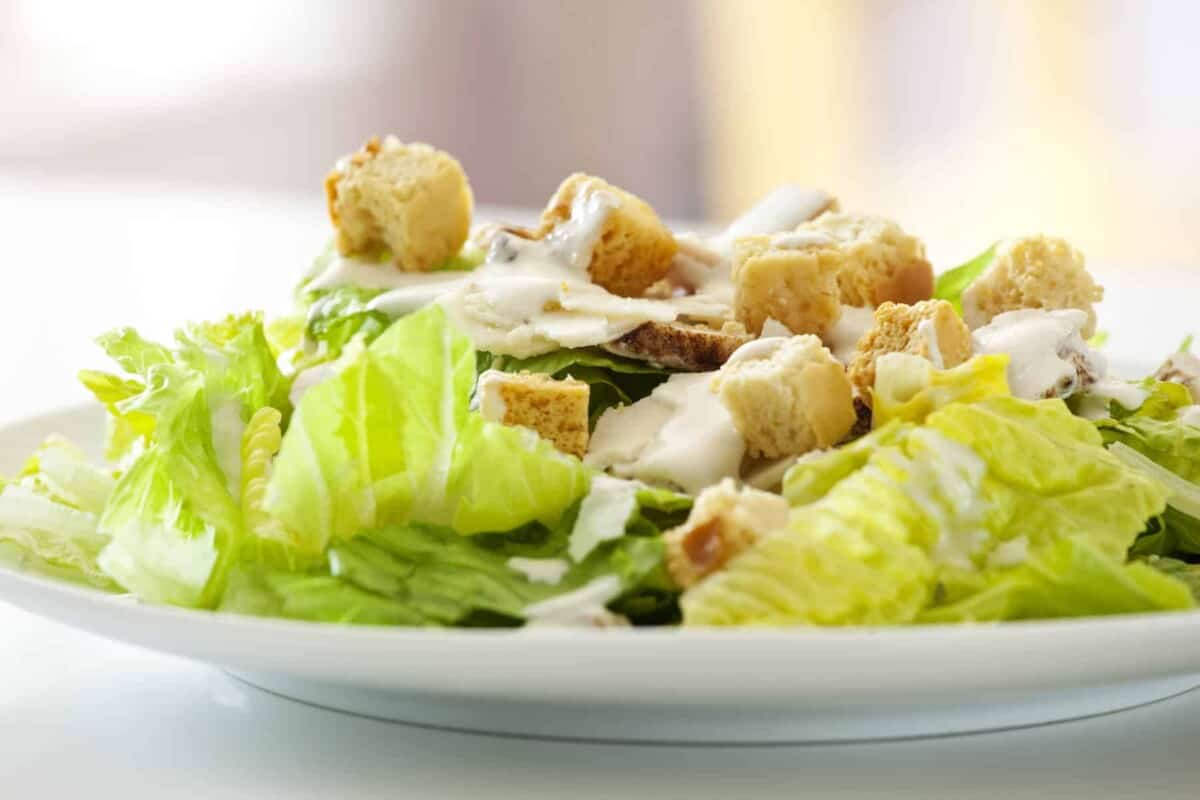 classic chicken caesar salad with lettuce, chicken, croutons, caesar dressing and a sprinkle of pepper.