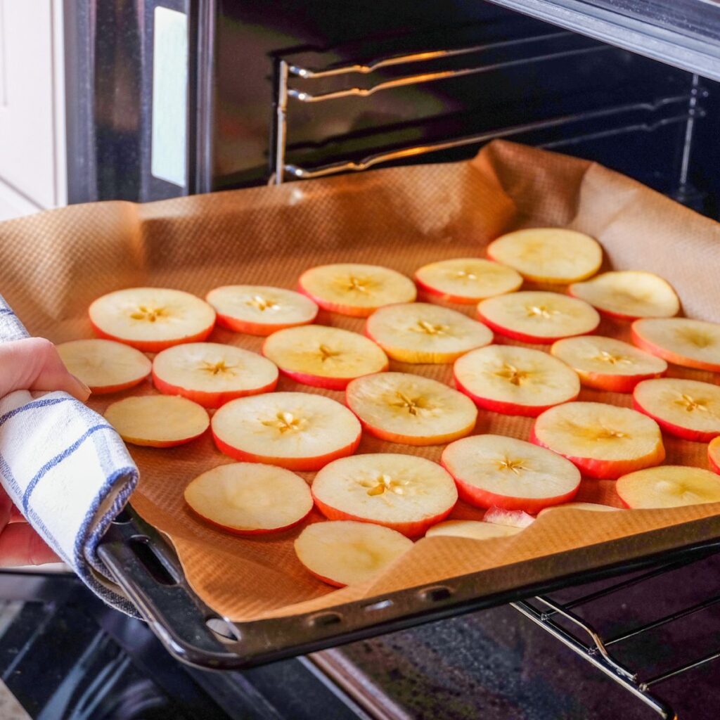 Washed sliced apples placed on a tray to dry in the oven.