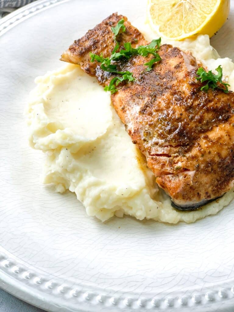 Baked Blackened salmon served with mashed potatoes and garnished with parsley