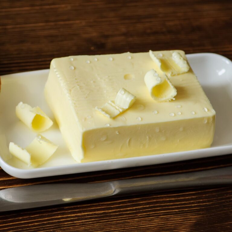 A piece of butter on a white plate.
