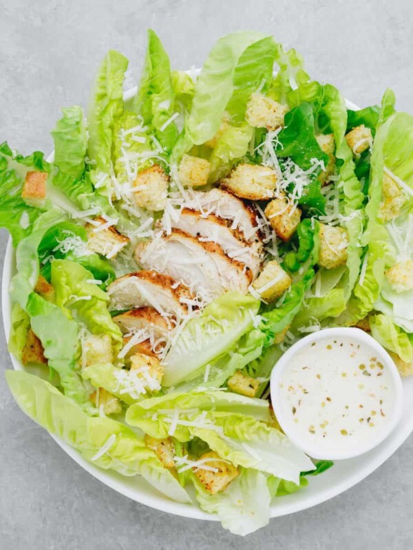 a top view of Caesar salad, with romaine lettuce hearts, croutons, parmesan cheese, and homemade Caesar salad dressing