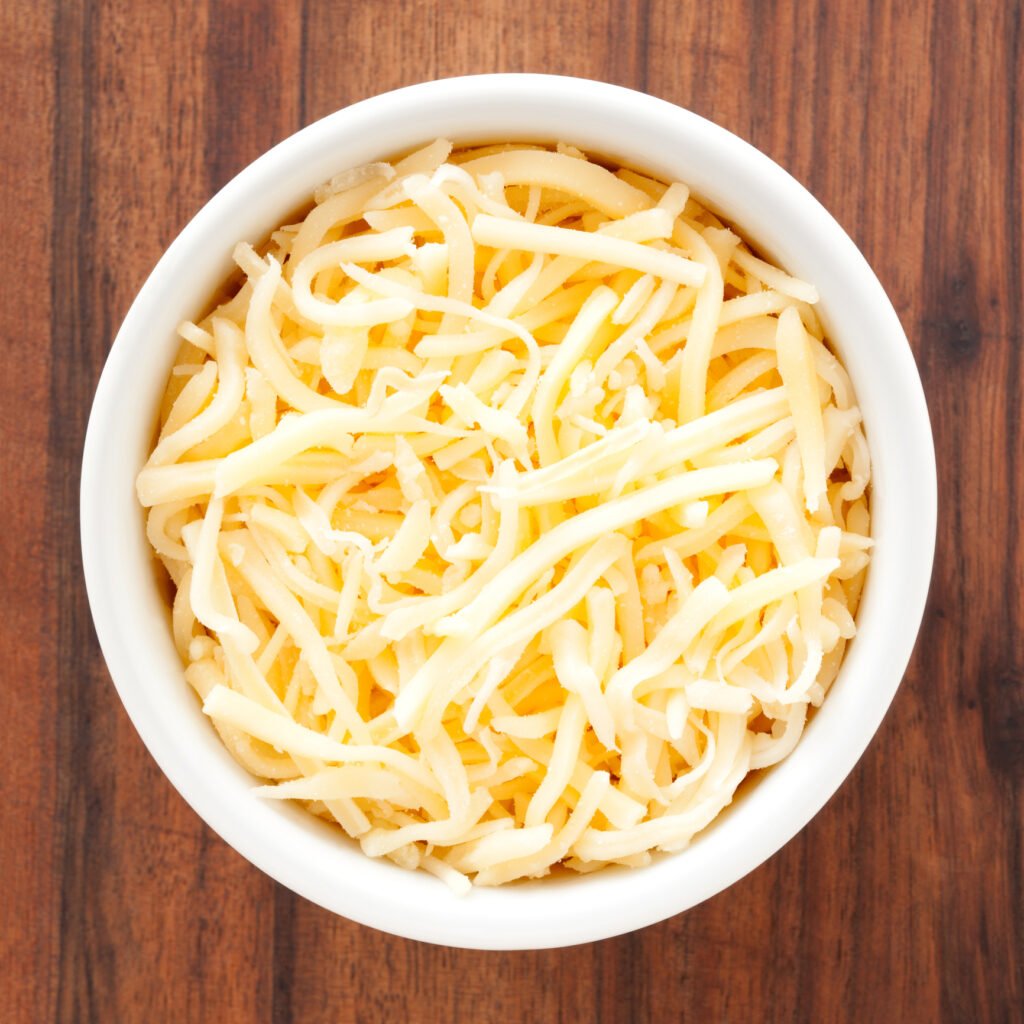 a white bowl that contains shredded mozzarella cheese