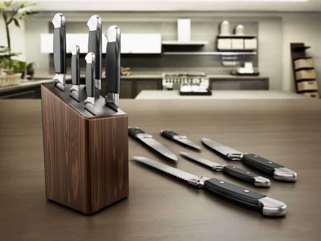 Set of kitchen knives standing on a brown table.