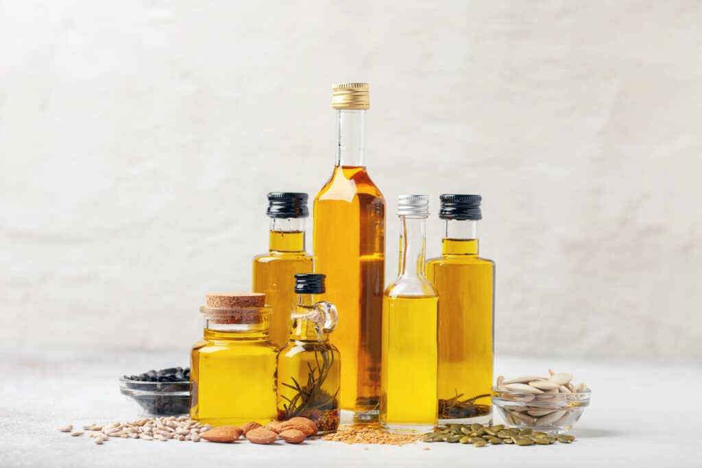 Various vegetable and nut oil in bottles on a bright background.