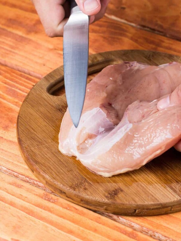 Raw chicken breasts fillet on the round kitchen wooden board.