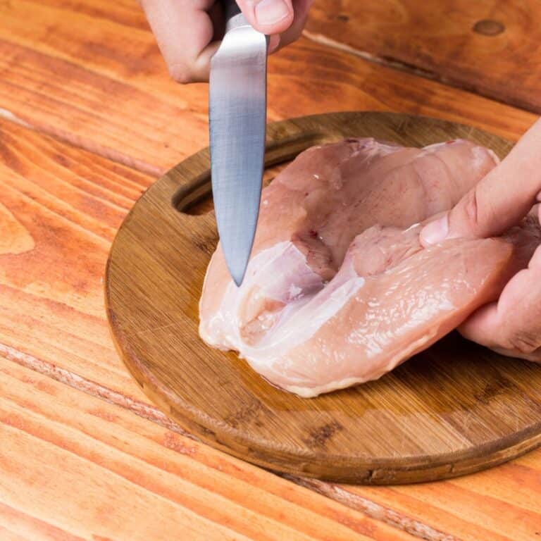 Raw chicken breasts fillet on the round kitchen wooden board.