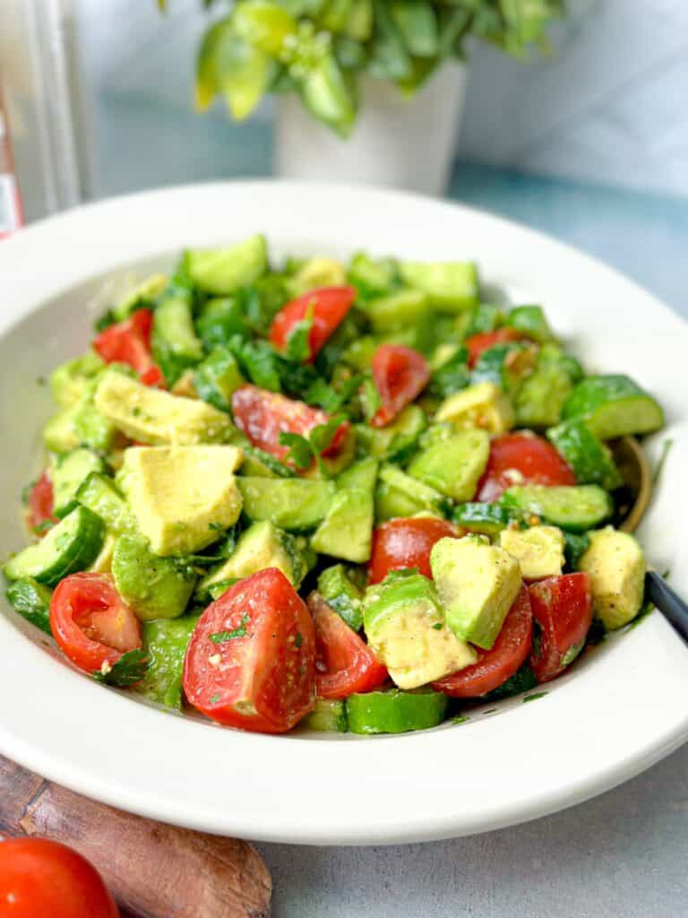 a cucumber avocado dish with tomatoes, dressed with olive oil and lemon