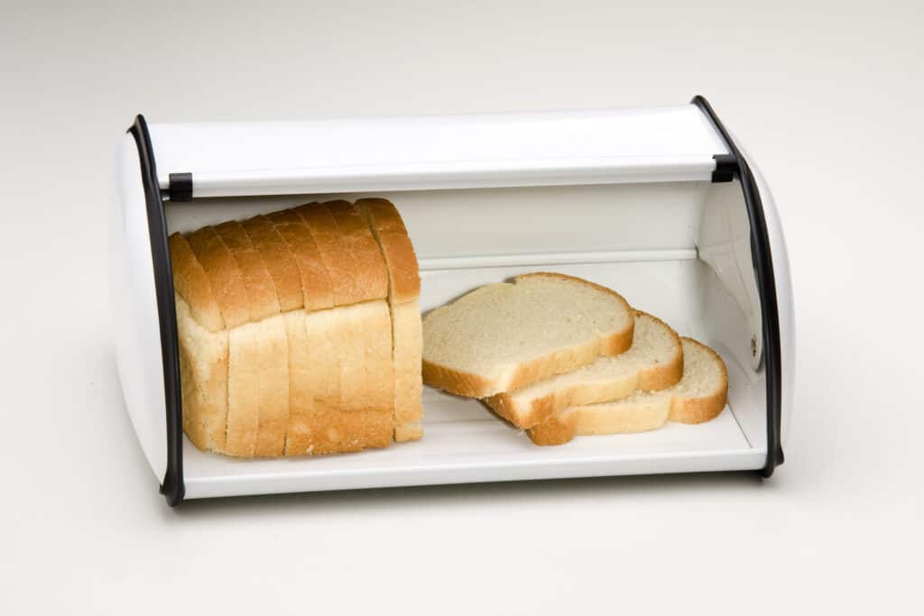 slices of bread stored in a white metal bread box open