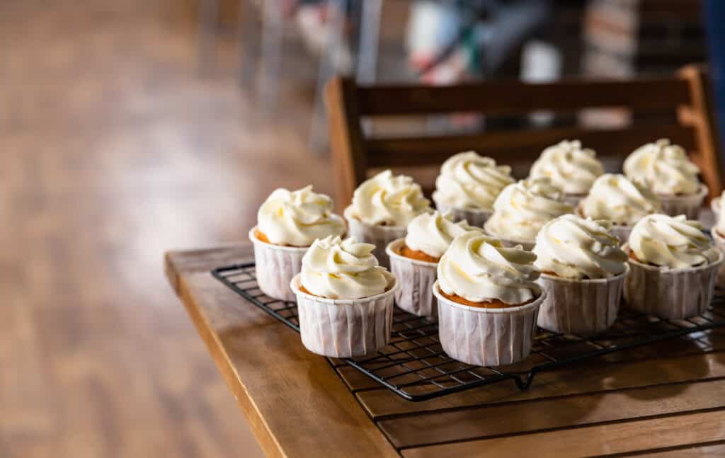 Delicious homemade vanilla cupcakes with cream cheese frosting on a metal grille