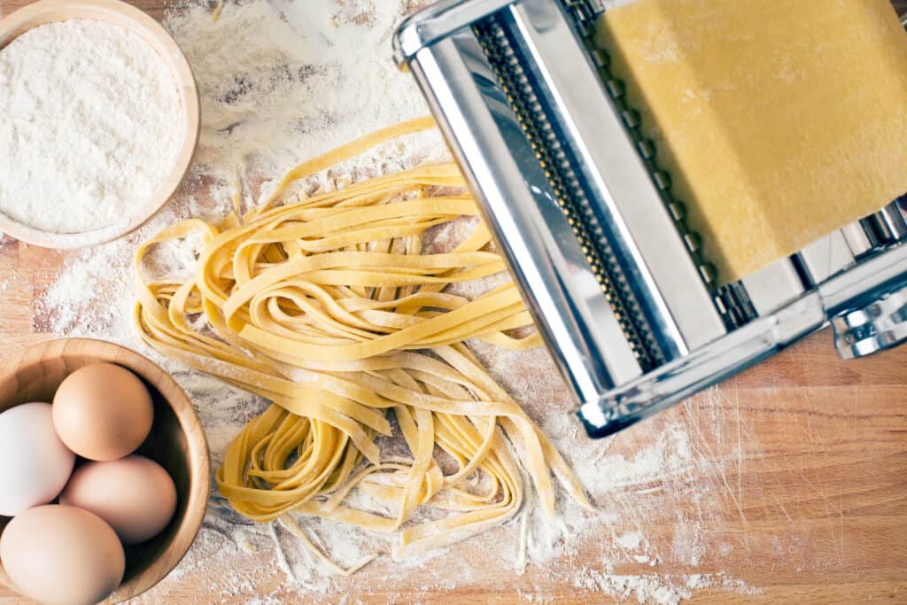 fresh pasta and pasta press machine on kitchen table