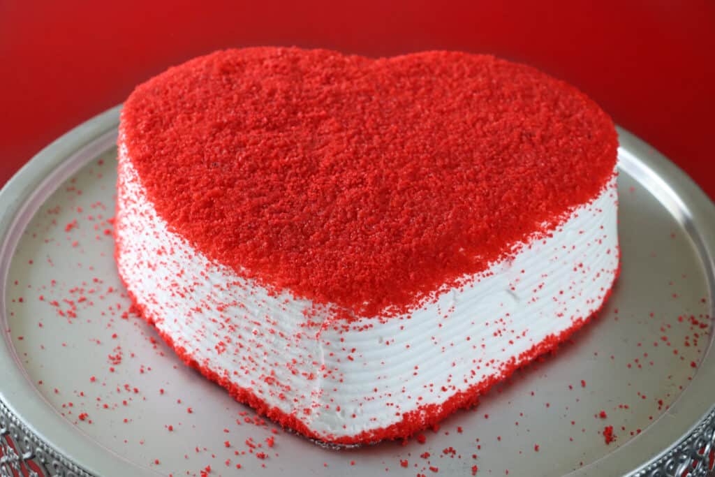 A heart-shaped red velvet cake topped with butter cream and embellished with dried raspberry powder was made with basic decorating techniques.