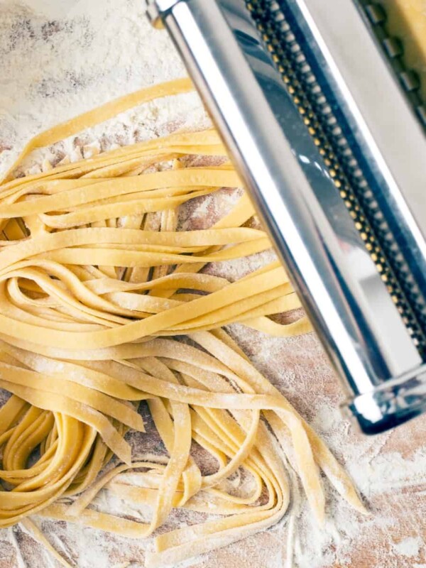 fresh pasta and pasta press machine on wooden table
