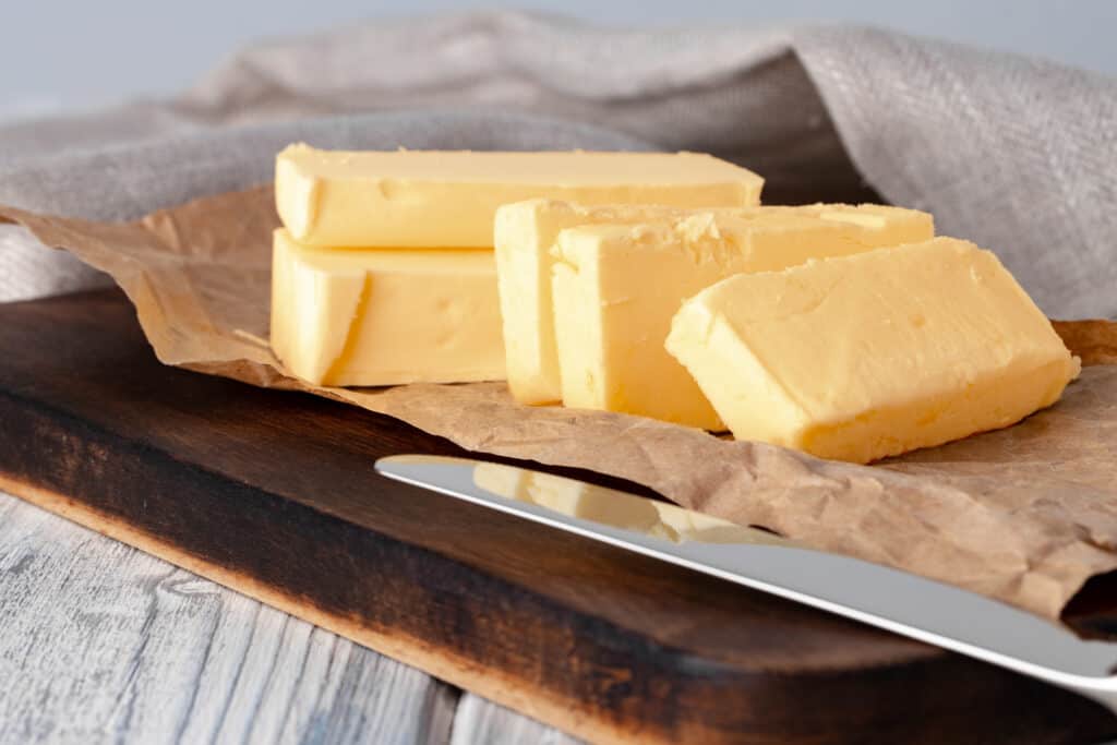 pieces of butter sliced almost equally on a wooden cutting board