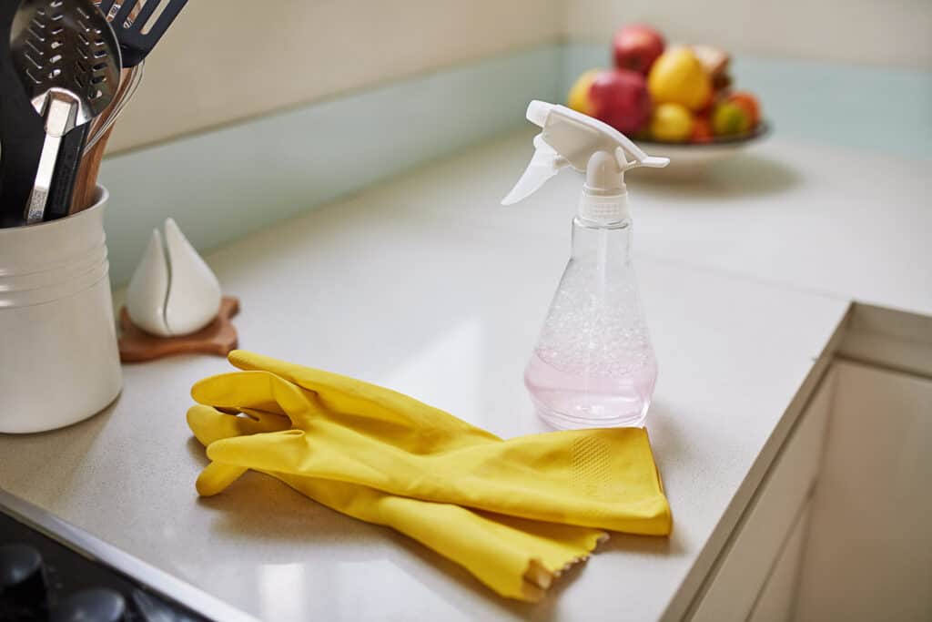 Shot of a pair of rubber gloves and disinfect spray on a kitchen counter at home