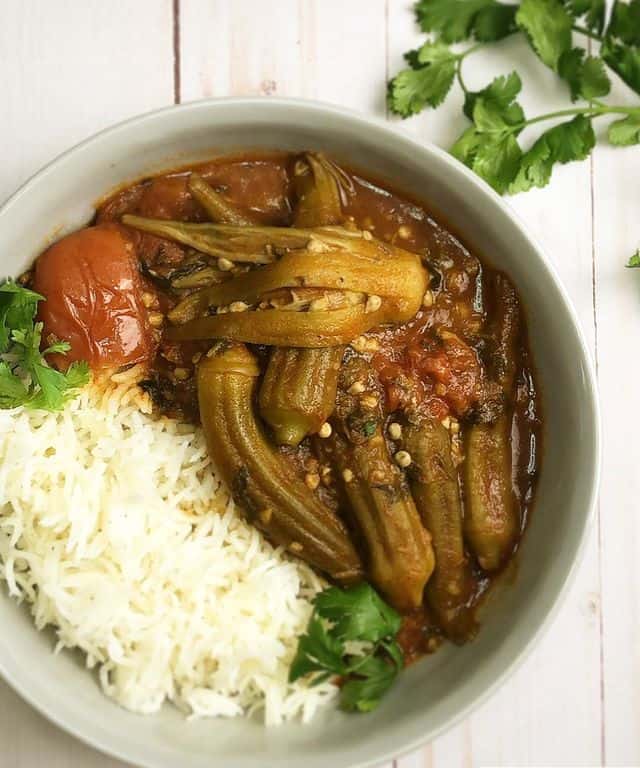 A hearty dish of okra stew made with beef shanks, sautéed garlic and cilantro, frozen baby okra, and thickened tomato-based broth and served with warm basmati rice.