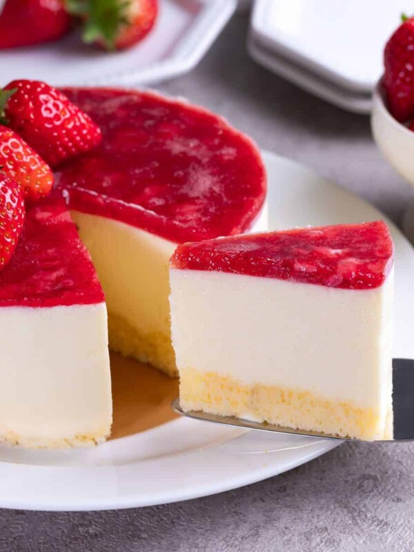 a mouthwatering served strawberry cheesecake topped with strawberry jam and fresh strawberry fruits