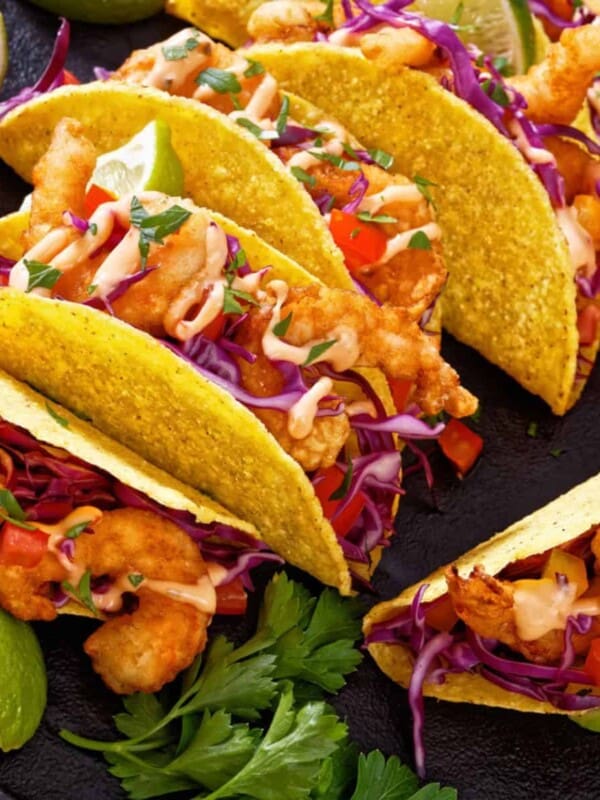 a close up view of fish tacos drizzled with bang bang sauce