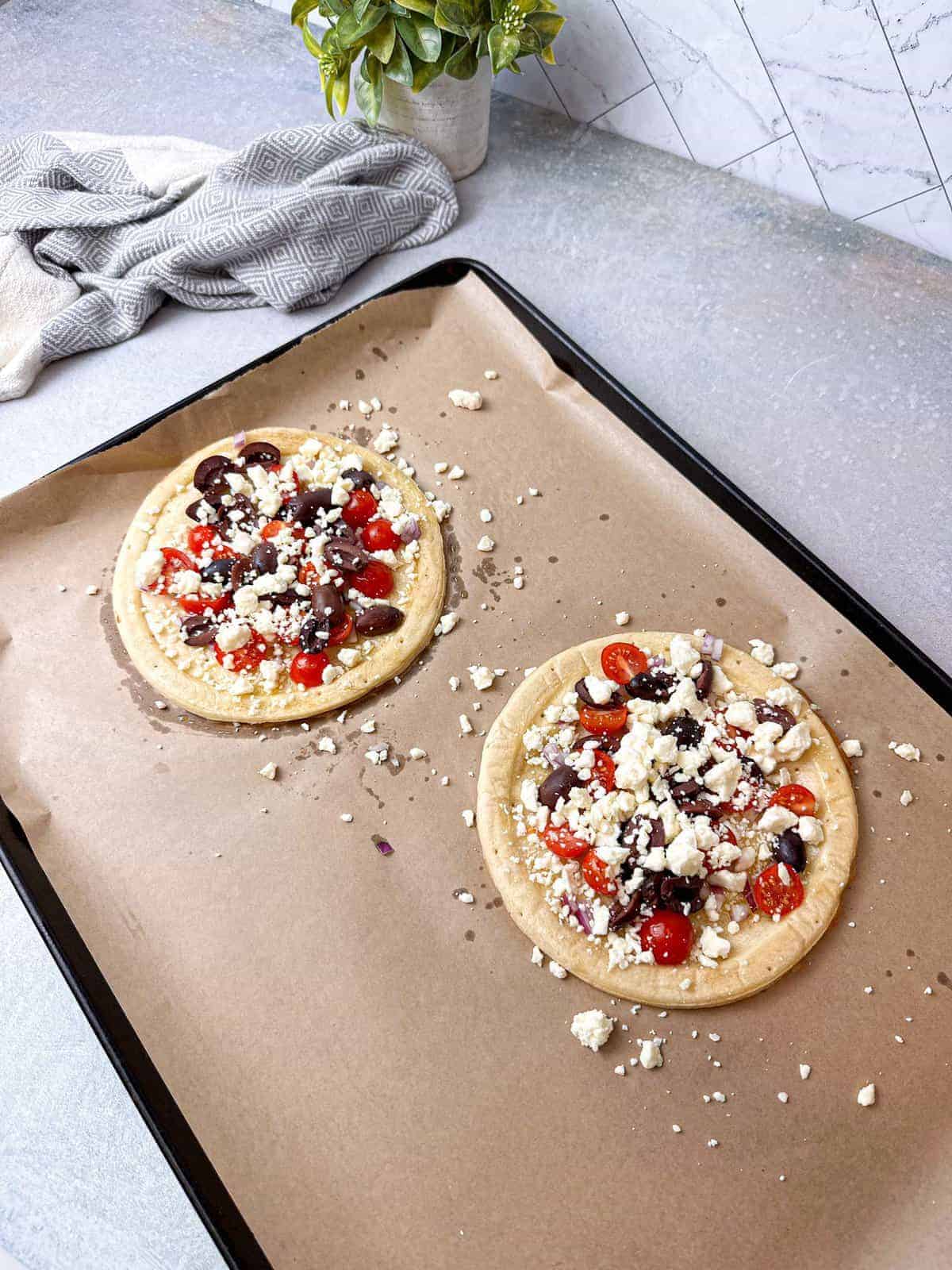 Drizzling tzatziki sauce all over the pizza and garnishing it with sliced Kalamata olives after it was baked in the oven