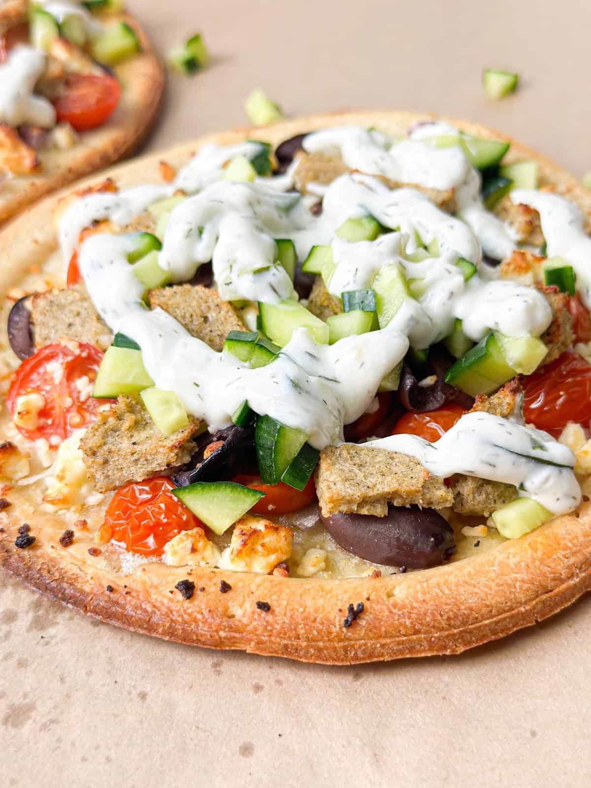 a close up shot of Mediterranean flatbread pizza created from scratch with cherry tomatoes, olives, feta, gyro meat, and more