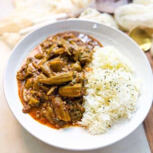 a close up shot of a plate of okra stew served with white rice