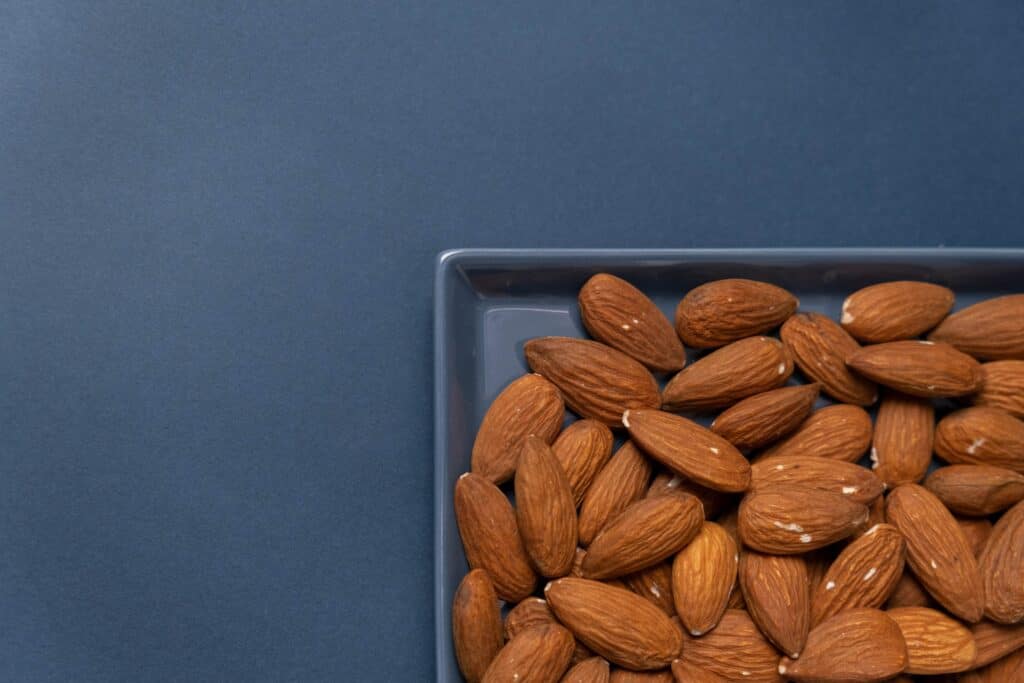A plate filled with raw almonds to be toasted